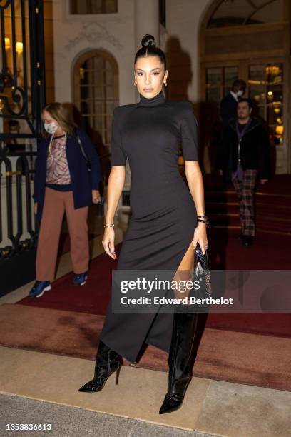 Guest wears gold and diamonds earrings, a black turtleneck / short sleeves / epaulets slit midi tube dress, a gold bracelet, a black shiny leather...