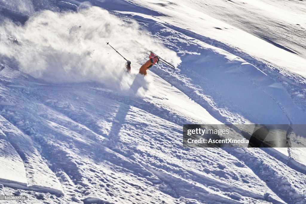 Skier falls down at speed, on snowy mountain ridge