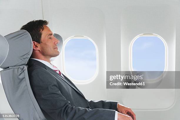 germany, bavaria, munich, mid adult businessman relaxing in business class airplane cabin - airplane seats stock pictures, royalty-free photos & images