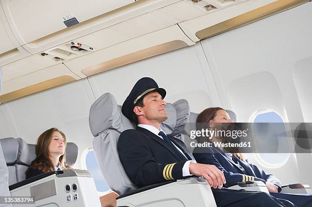 germany, bavaria, munich, mid adult flight personnels and stewardess resting in business class airplane cabin - man sleeping with cap stock pictures, royalty-free photos & images