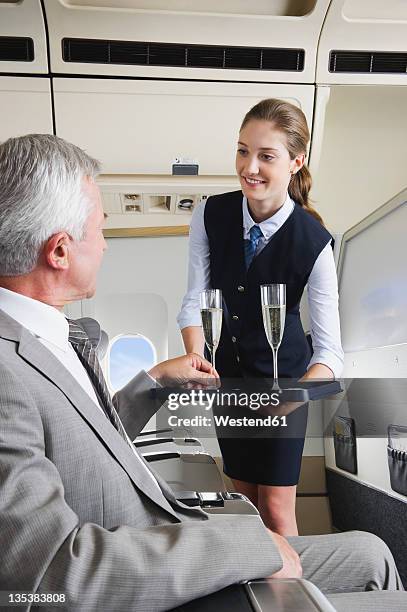 germany, bavaria, munich, young stewardess serving champagne to senior businessman in business class airplane cabin - 客室乗務員 ストックフォトと画像
