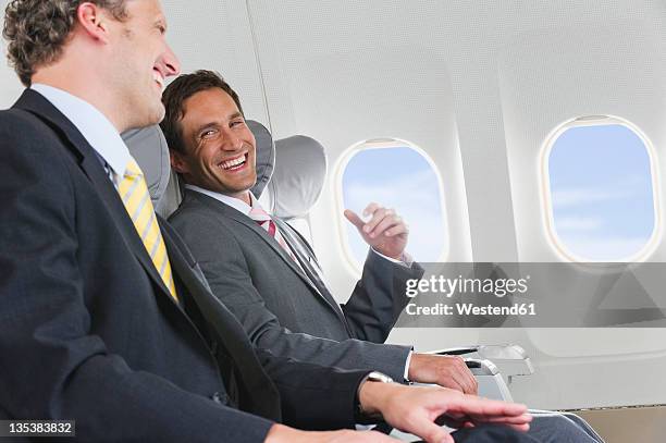 germany, bavaria, munich, businessmen talking in business class airplane cabin - flugzeugsitz stock-fotos und bilder