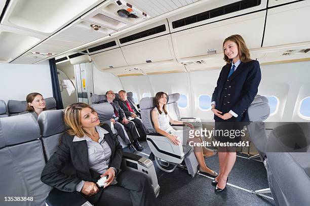 germany, bavaria, munich, stewardess and passengers in business class airplane cabin, smiling - cabin crew stock-fotos und bilder