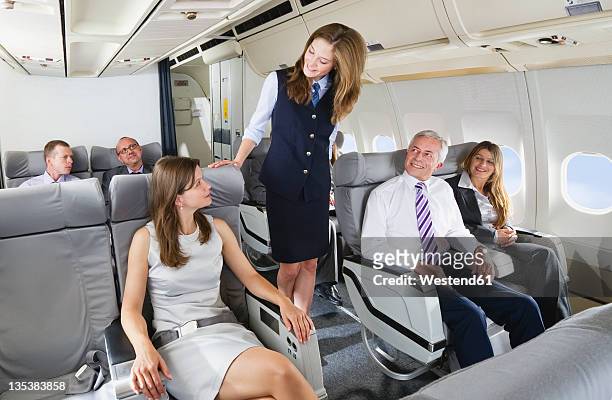 germany, bavaria, munich, stewardess and passengers in business class airplane cabin, smiling - air stewardess stock pictures, royalty-free photos & images