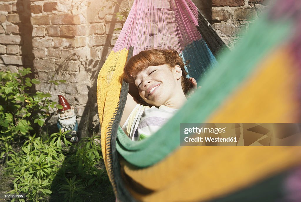 Germany, Berlin, Young woman in hammock, smiling