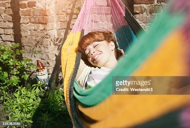 germany, berlin, young woman in hammock, smiling - hammock foto e immagini stock