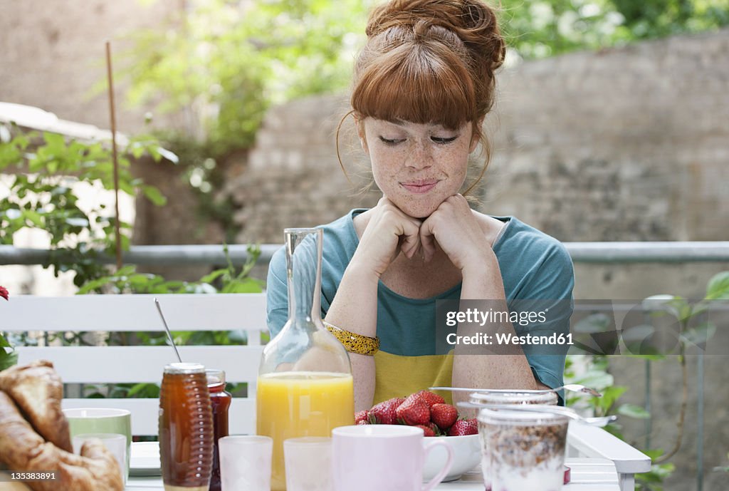 Germany, Berlin, Young woman at lunch table, smiling