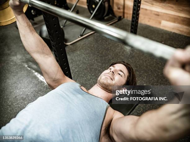 junger mann hebt gewichte im fitnessstudio - lifting weights stock-fotos und bilder