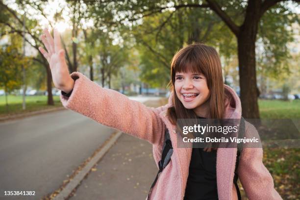 happy young girl waving her hand and smiling - messestand bildbanksfoton och bilder