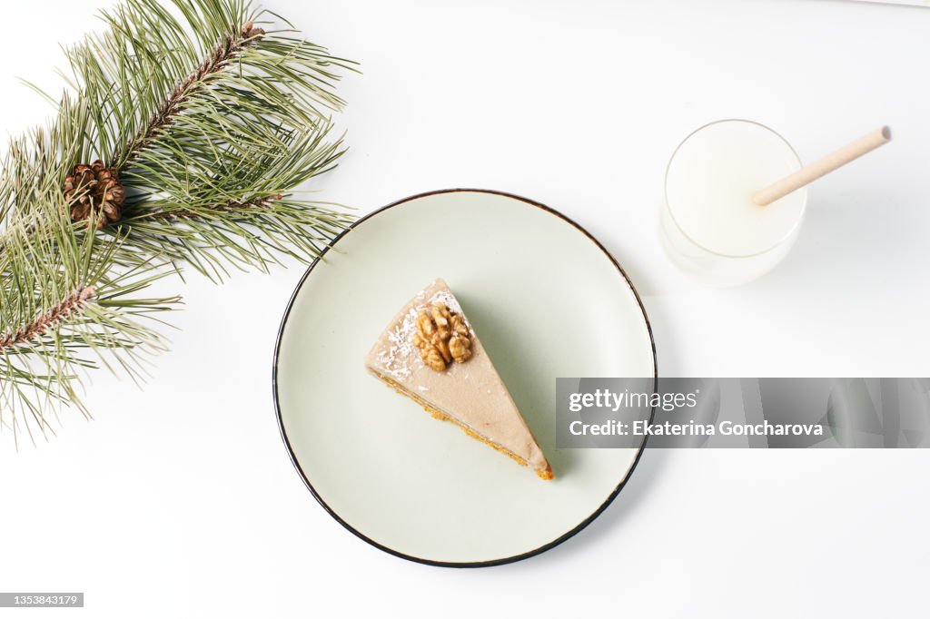 A vegetarian piece of cake on a plate and a glass of potato or oat milk on white background