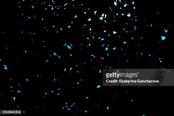a scattering of blue fragments on a black background. - coriandoli foto e immagini stock