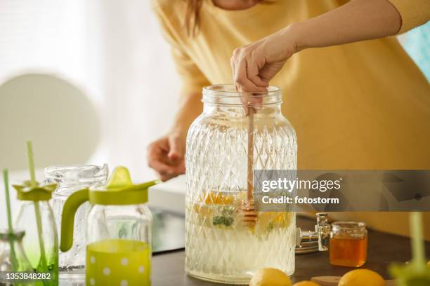 woman sweetening lemonade with honey - lemon juice stock pictures, royalty-free photos & images