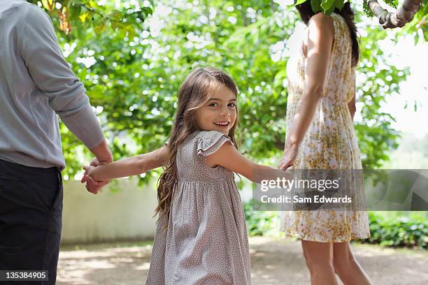 family holding hands together outdoors - girl looking over shoulder stock pictures, royalty-free photos & images