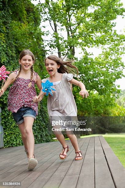 girls running holding pinwheels - children only stock pictures, royalty-free photos & images