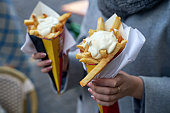 Belgian frites or french fries with mayonnaise in Brussels, Belgium. Female tourist holds two portions of fries in hands in the street.