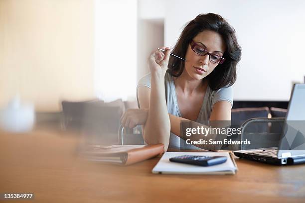 woman sitting at desk looking at notebook - uncertainty stock pictures, royalty-free photos & images
