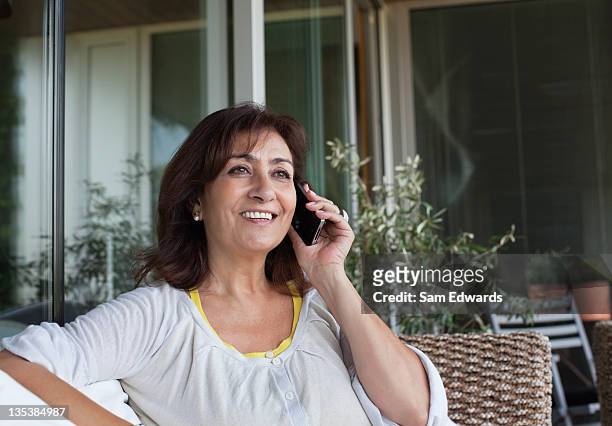 woman sitting on patio talking on cell phone - answering stock pictures, royalty-free photos & images