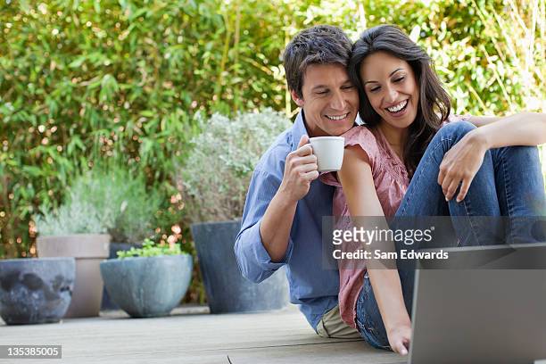 couple relaxing on patio with laptop and coffee - coffee on patio stock pictures, royalty-free photos & images