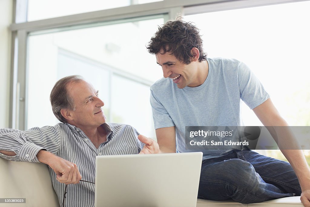 Men sitting on sofa using laptop together