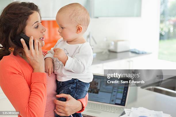 mother holding baby and talking on cell phone - samuser stock pictures, royalty-free photos & images