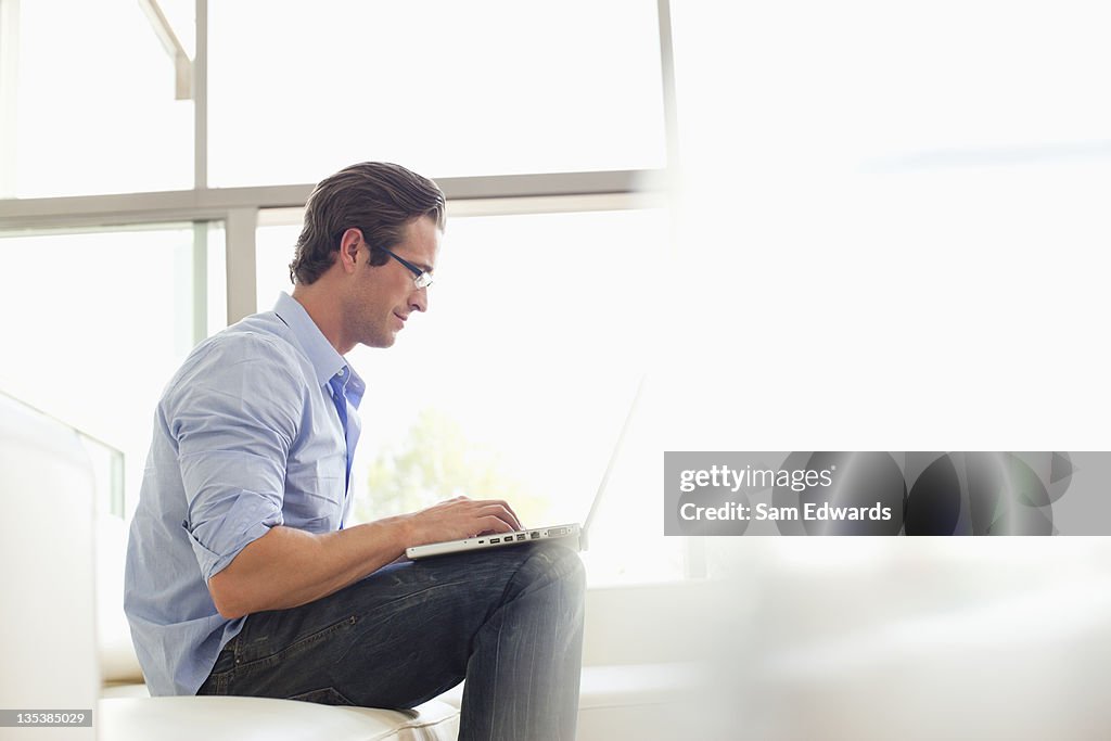 Hombre sentado en el sofá usando una computadora portátil
