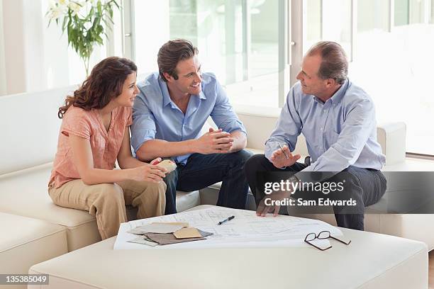 couple sitting on sofa talking to financial advisor - model home stock pictures, royalty-free photos & images