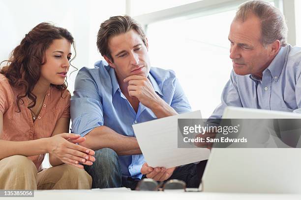 couple going over paperwork with financial advisor - verkoper stockfoto's en -beelden