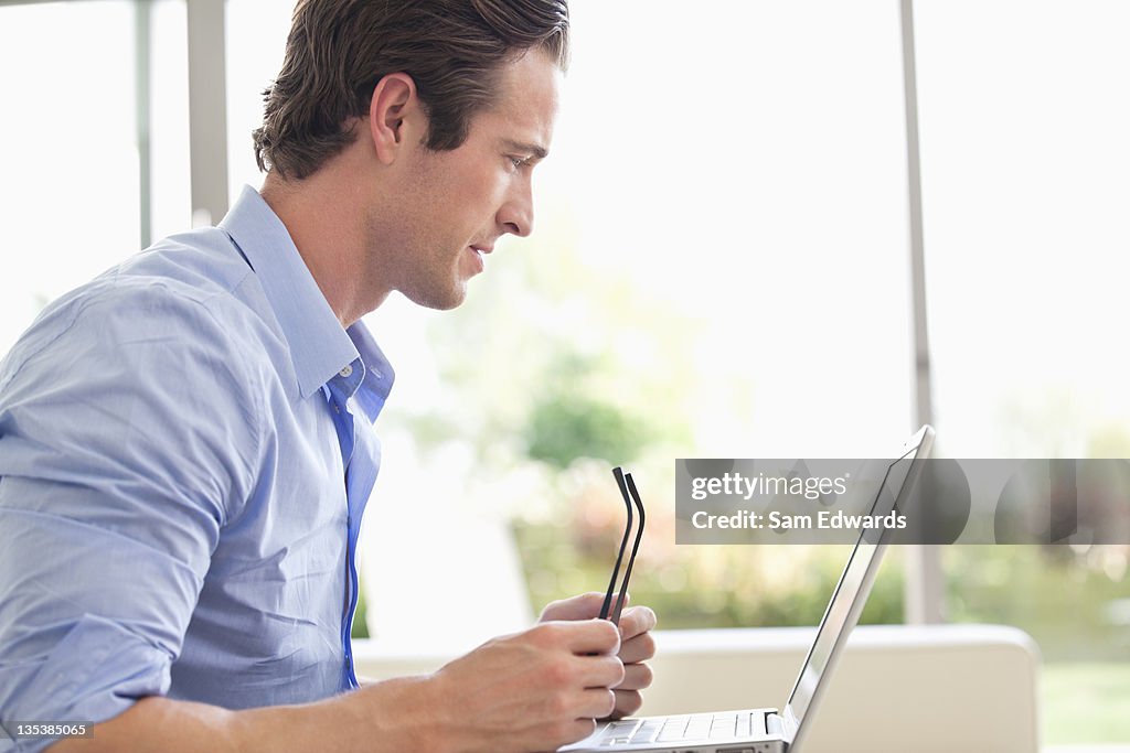 Mann hält eyeglasses Blick auf laptop