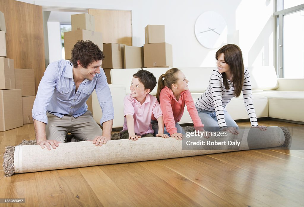 Family unrolling carpet together in new home