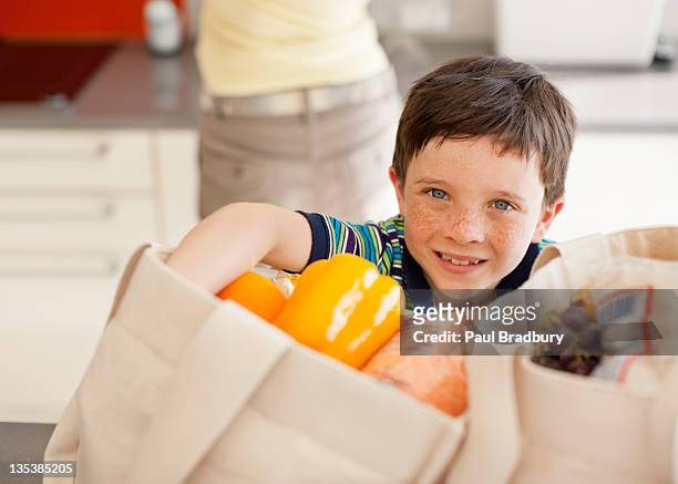 boy unloading groceries from reusable bag - putting away stock pictures, royalty-free photos & images
