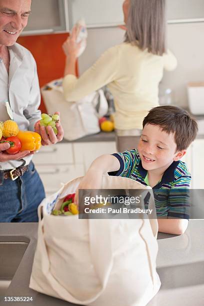 junge hilft bei entspannung lebensmittel von wiederverwendbare tasche - young man groceries kitchen stock-fotos und bilder