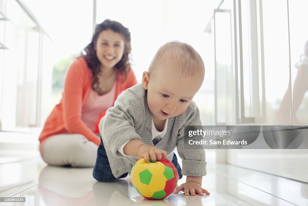 Madre viendo niños jugando con bola