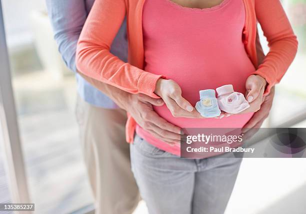 pregnant woman holding baby booties - baby boot stock pictures, royalty-free photos & images