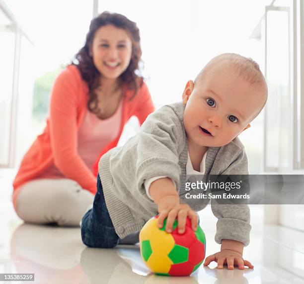 madre guardando il bambino giocando con la palla - baby football foto e immagini stock