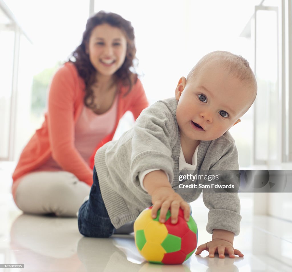 Mother watching baby playing with ball