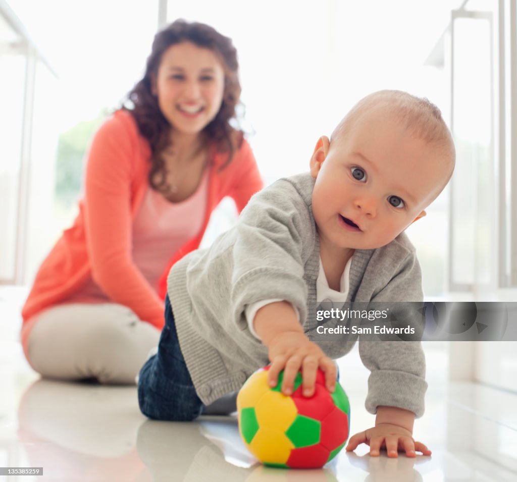 Mãe assistindo bebê brincando com bola