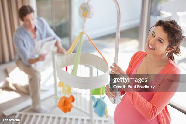 expectant mother looking at crib mobile - baby crib stock pictures, royalty-free photos & images