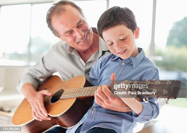 grandfather teaching grandson to play the guitar - teach muziekinstrument stockfoto's en -beelden