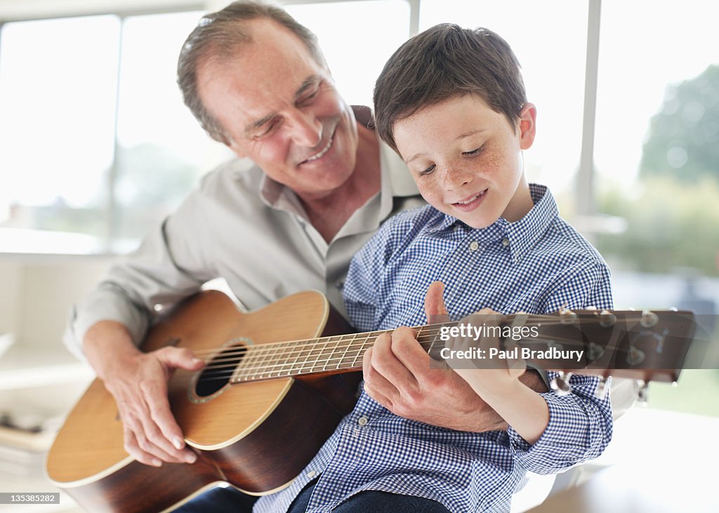 Grandfather teaching grandson to play the guitar