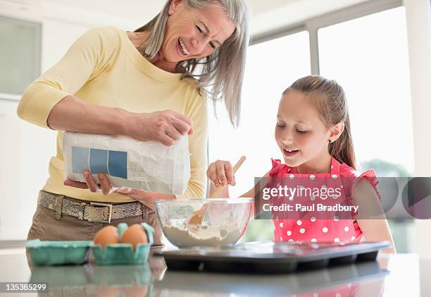 grandmother and granddaughter baking cupcakes together - flour bag stockfoto's en -beelden