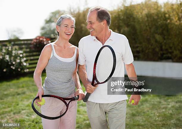 couple outdoors holding tennis rackets - tennis woman stockfoto's en -beelden