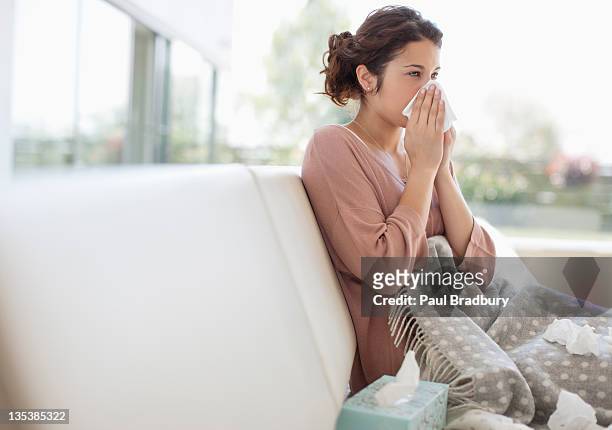 sick mujer soplando su nariz - illness fotografías e imágenes de stock