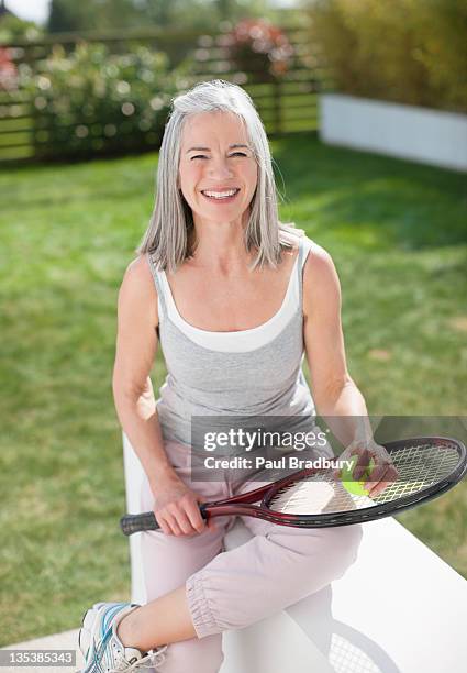 lächelnde frau mit tennisschläger - lawn tennis stock-fotos und bilder