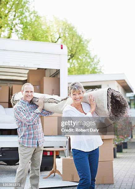 couple carrying carpet from moving van - old moving van stock pictures, royalty-free photos & images