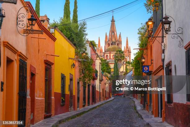 city street leading to a parish church in san miguel de allende, mexico - guanajuato stock pictures, royalty-free photos & images