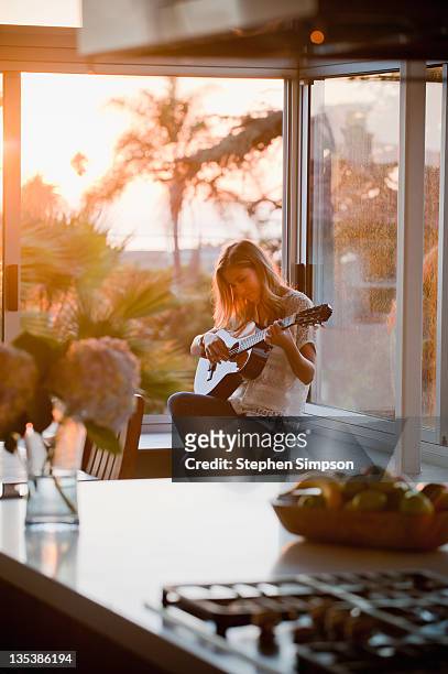 woman in window playing guitar - playing music photos et images de collection