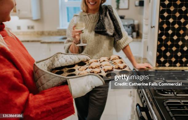 a woman removes freshly baked home made mince pies from an oven - christmas togetherness stock pictures, royalty-free photos & images