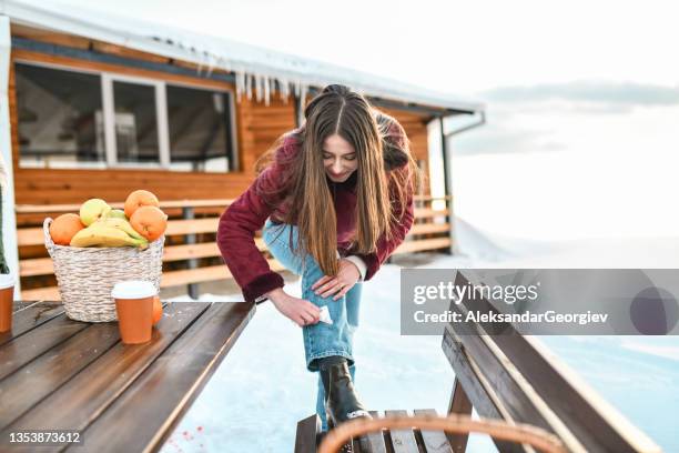 smiling female wiping jeans clean from spilt coffee and juice on snowy mountain - spilling bildbanksfoton och bilder