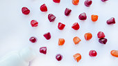 Group of red, orange and purple multivitamin gummies with the bottle isolated on white background