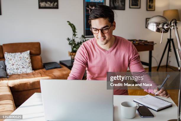 un jeune homme travaille sur un ordinateur portable - young man laptop couch photos et images de collection